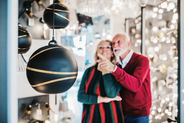 Coppia senior nel negozio di illuminazione domestica che sceglie shandelier per la loro casa