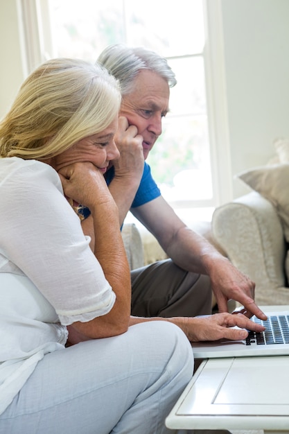 coppia senior seria con laptop a casa