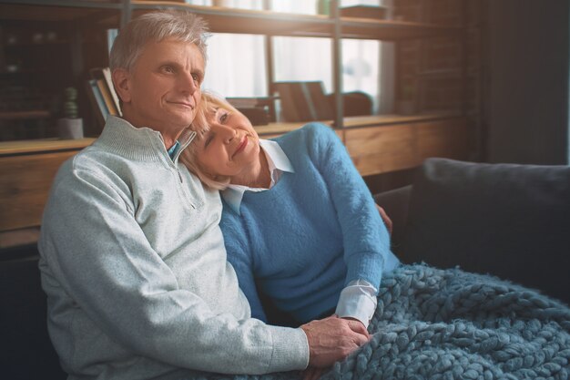 Coppia senior sono seduti insieme sul divano.