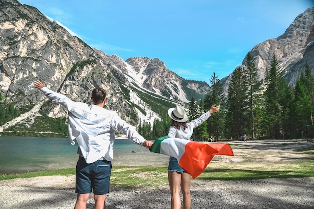 Coppia sorridente con bandiera italiana al lago di Braies in Italia