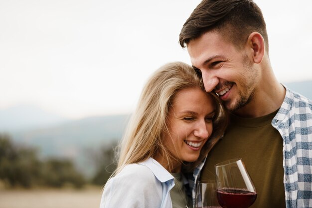 Coppia sorridente tostatura bicchieri di vino all'aperto in montagna