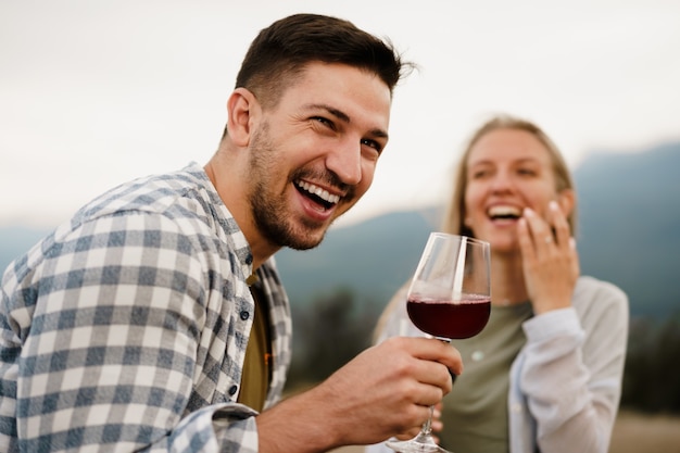 Coppia sorridente tostatura bicchieri di vino all'aperto in montagna