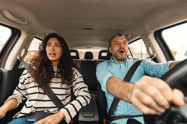 Coppia spaventata che guida la vista del parabrezza del ritratto anteriore dell'auto