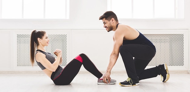 Coppia sportiva che fa sit up uno per uno in studio di luce, panorama, spazio di copia