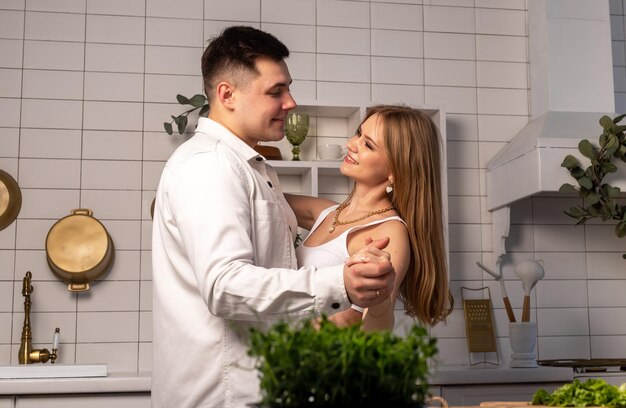 Coppia sposata che balla in cucina marito e moglie sorridenti che si guardano con amore felice e