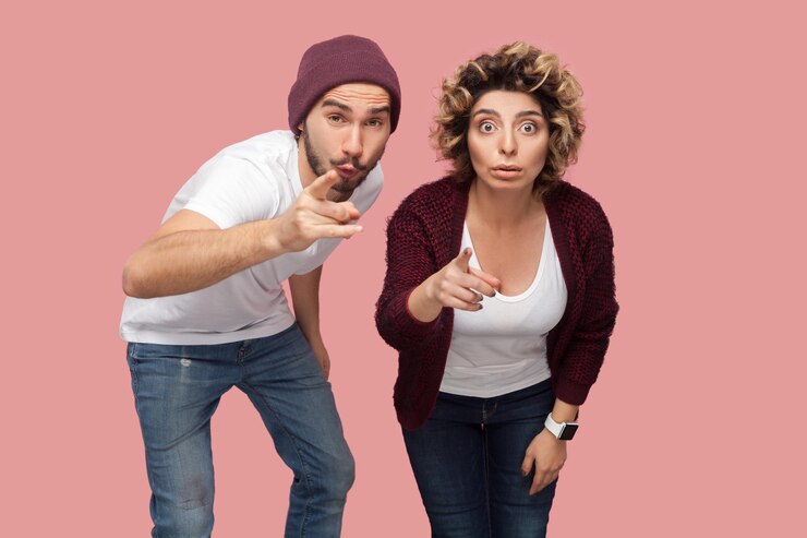 Coppia stupita di amici che puntano alla telecamera scegliendoti guardando con grandi occhi stupiti