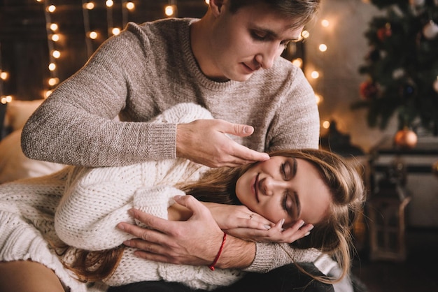 Coppia sul letto in camera da letto. Interni scuri. Capodanno e Natale. Baci e abbracci. Amore. Maglione bianco e calzini alti. Incontro romantico. Una data amanti.