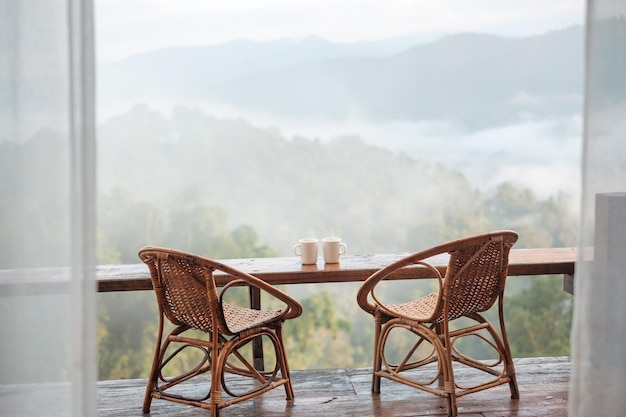 Coppia Tazza bianca di caffè o tè caldo su un tavolo di legno al mattino con sfondo di montagna e natura