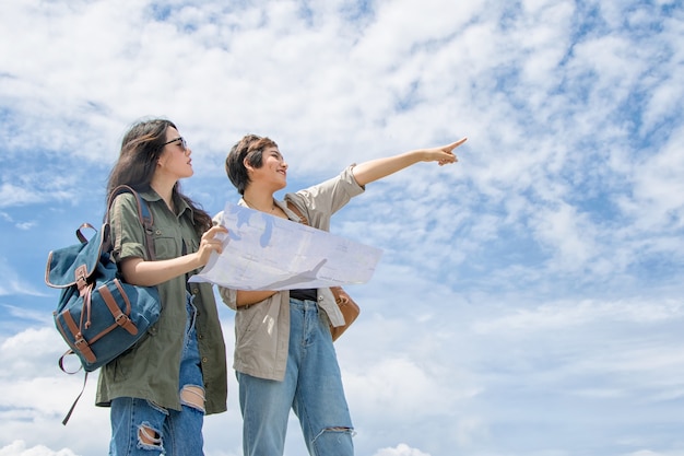 Coppia turistica utilizzando una mappa per trovare la posizione sotto il cielo blu