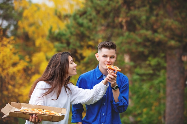 Coppia un uomo e una donna giovane divertente bella godere della pizza e socializzare su un picnic nella natura insieme