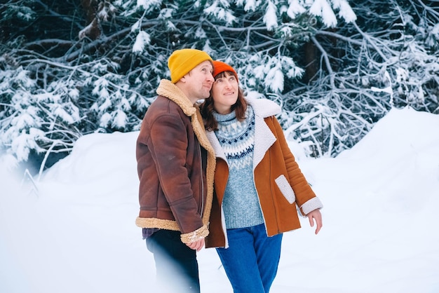 Coppia uomo e donna che si abbracciano su uno sfondo di foresta innevata