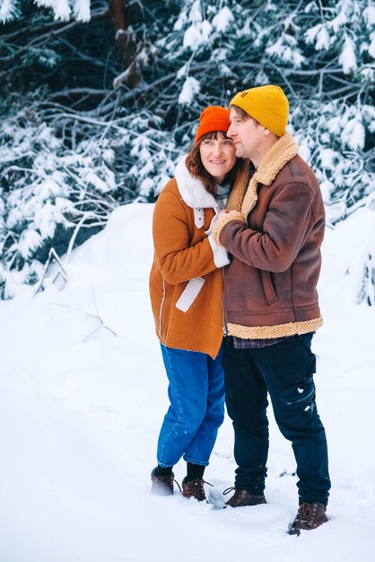 Coppia uomo e donna che si abbracciano su uno sfondo di foresta innevata