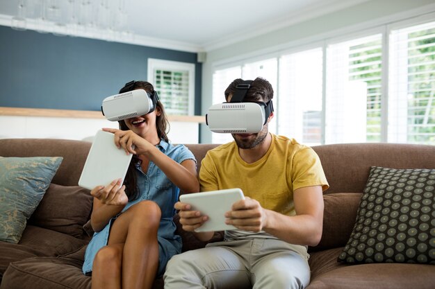 Coppia utilizzando le cuffie da realtà virtuale nel soggiorno di casa