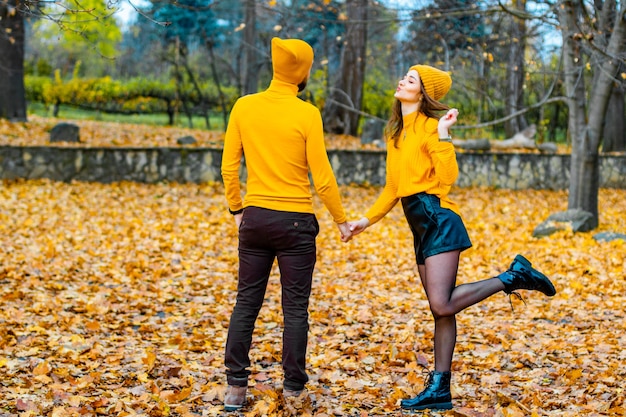 Coppia vestita in dolcevita giallo e cappelli gialli nel parco in autunno