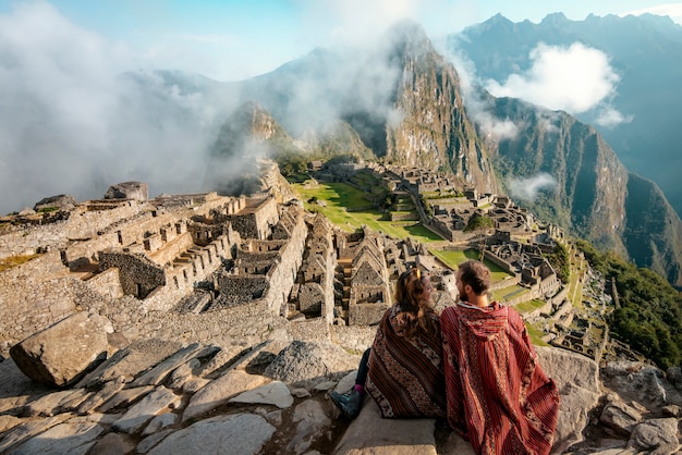 Coppia vestita in poncho a guardare le rovine di Machu Picchu