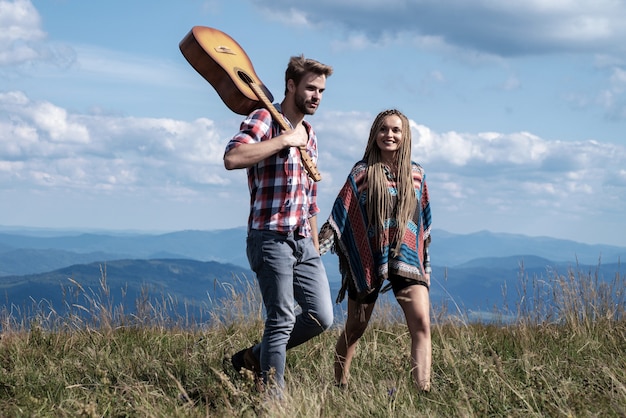 Coppia viaggiatori uomo e donna seguono mano nella mano al paesaggio di montagne soleggiate