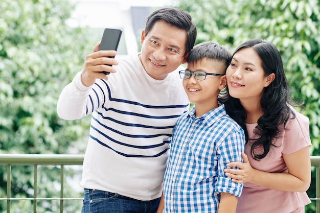 Coppia vietnamita uomo prendendo selfie con moglie e figlio preadolescente sul balcone