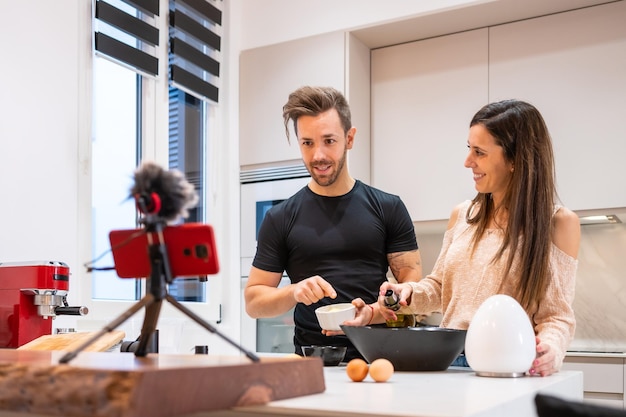 Coppia vlogger di cibo che realizza video mentre prepara le verdure in cucina