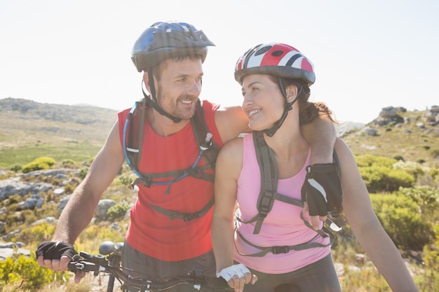 Coppie adatte del ciclista che sorridono insieme sulla traccia di montagna