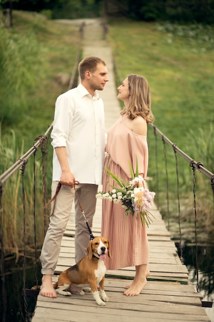 Coppie adorabili che camminano con il cane sul ponte.