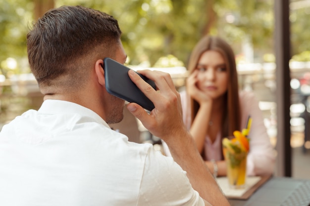 Coppie adorabili che godono in caffè facendo uso di tecnologia