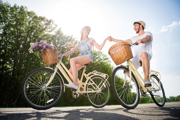 Coppie adorabili che propongono insieme all'aperto con le biciclette