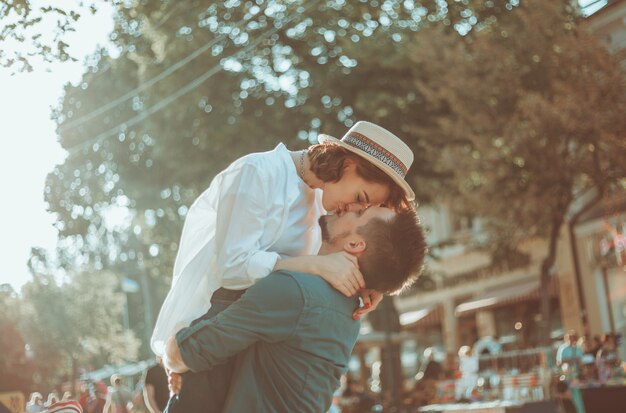 Coppie allegre allegre dei pantaloni a vita bassa nell'amore che bacia in una via della città. Il concetto romantico di innamorati. storia d'amore