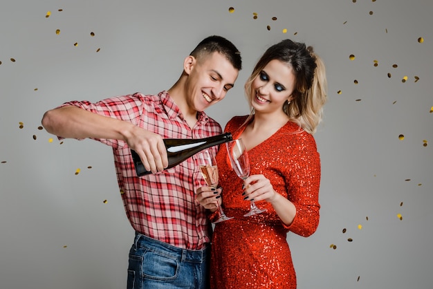 Coppie allegre felici che celebrano il nuovo anno che tengono i vetri con champagne sopra gray