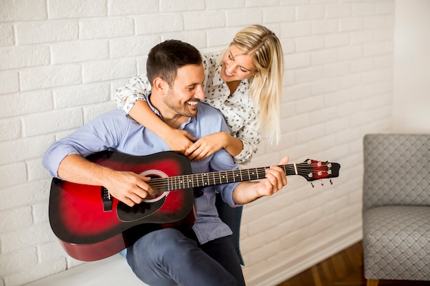Coppie amorose con la chitarra nella stanza a casa