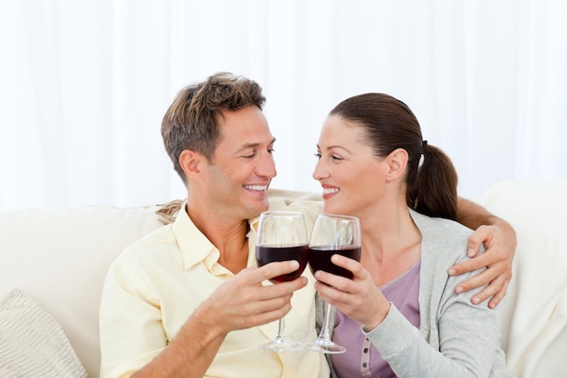Coppie appassionate che bevono vino rosso mentre rilassandosi sul sofà