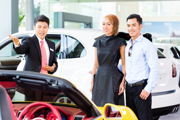 Coppie asiatiche che comprano automobile nella gestione commerciale