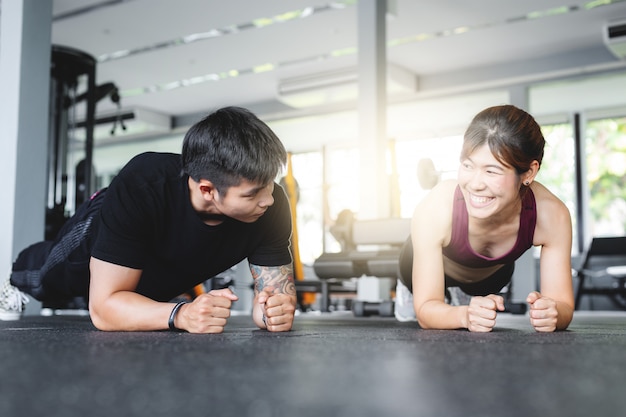 Coppie asiatiche che fanno flessioni in palestra.