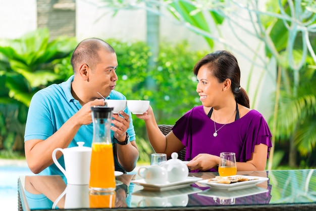 Coppie asiatiche che mangiano caffè sul portico domestico