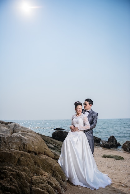 Coppie asiatiche che portano vestito da sposa e vestito per cerimonia di nozze della spiaggia