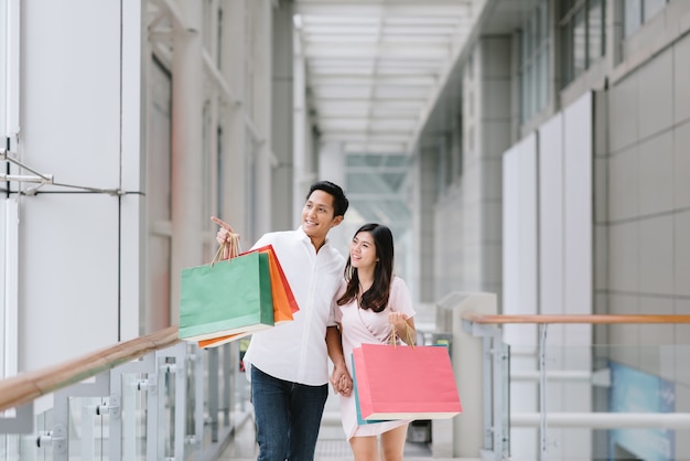 Coppie asiatiche felici che godono dell&#39;acquisto nel centro commerciale