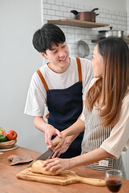Coppie asiatiche felici che hanno tempo romantico mentre cucinano preparando la cena in cucina insieme