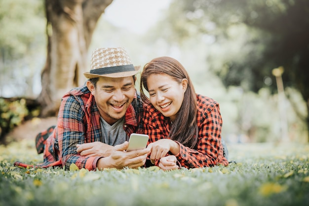 Coppie asiatiche felici facendo uso dello smartphone