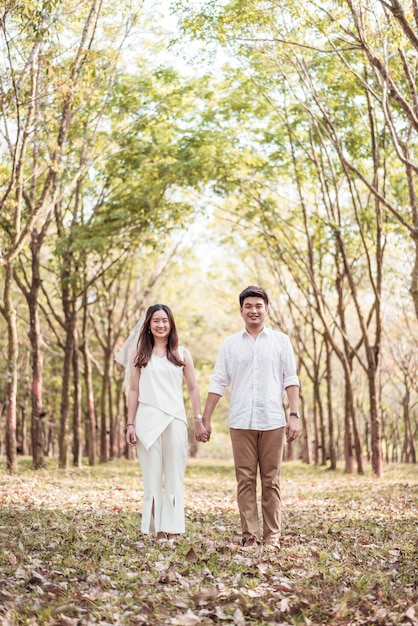 Coppie asiatiche felici nell'amore con l'arco dell'albero