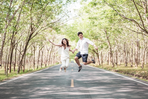 Coppie asiatiche felici nell'amore sulla strada con l'arco dell'albero