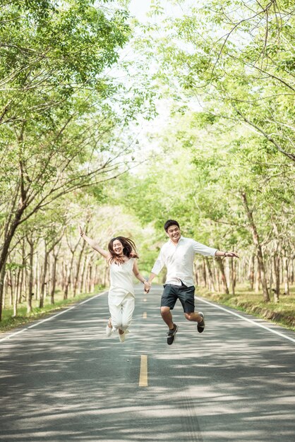 Coppie asiatiche felici nell'amore sulla strada con l'arco dell'albero