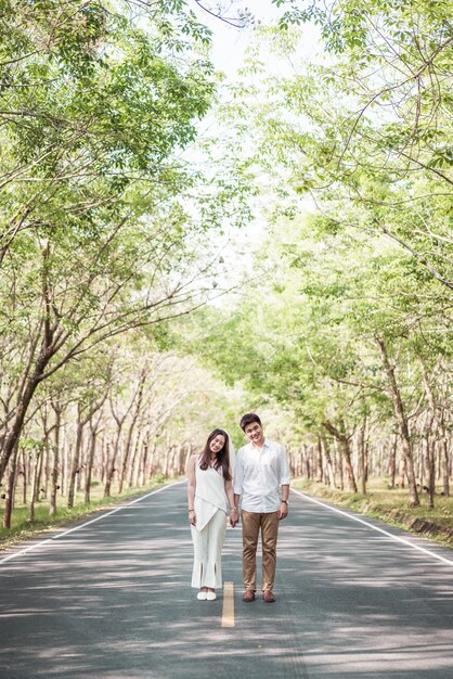 Coppie asiatiche felici nell'amore sulla strada con l'arco dell'albero