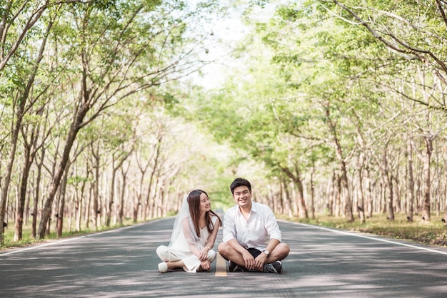 Coppie asiatiche felici nell'amore sulla strada con l'arco dell'albero