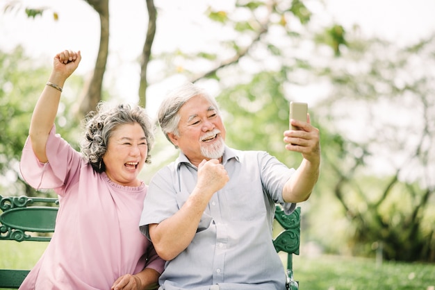 coppie asiatiche senior che ridono con lo smartphone