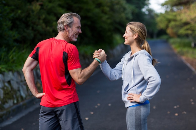 Coppie atletiche che si tengono per mano sulla strada aperta