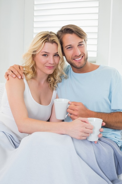 Coppie casuali sorridenti che si siedono sullo strato che mangia caffè