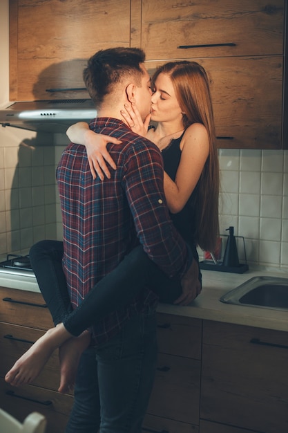 Coppie caucasiche che si baciano e si abbracciano in cucina durante la colazione