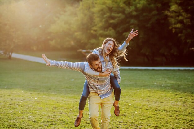 Coppie caucasiche sveglie nell'amore divertendosi sulle spalle e divertendosi in natura.