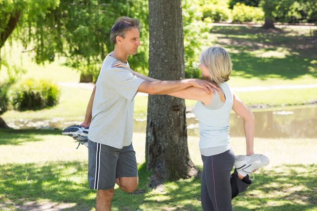 Coppie che allungano le gambe nel parco