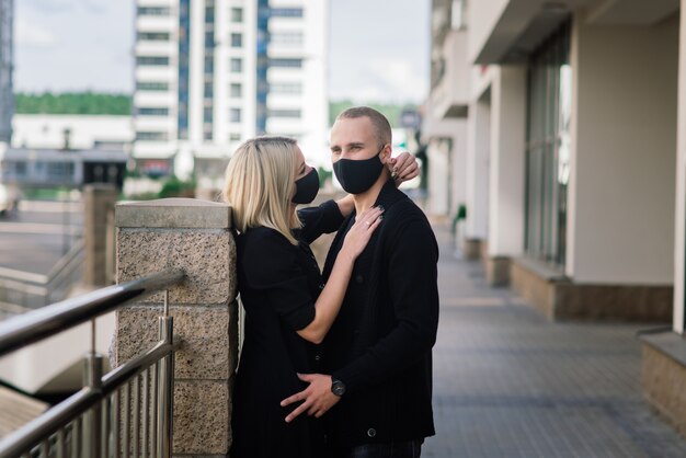 Coppie che indossano maschere protettive alla moda, camminando in una strada vuota della città durante la quarantena