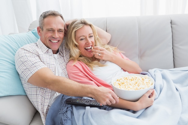 Coppie che mangiano popcorn mentre guardano la televisione